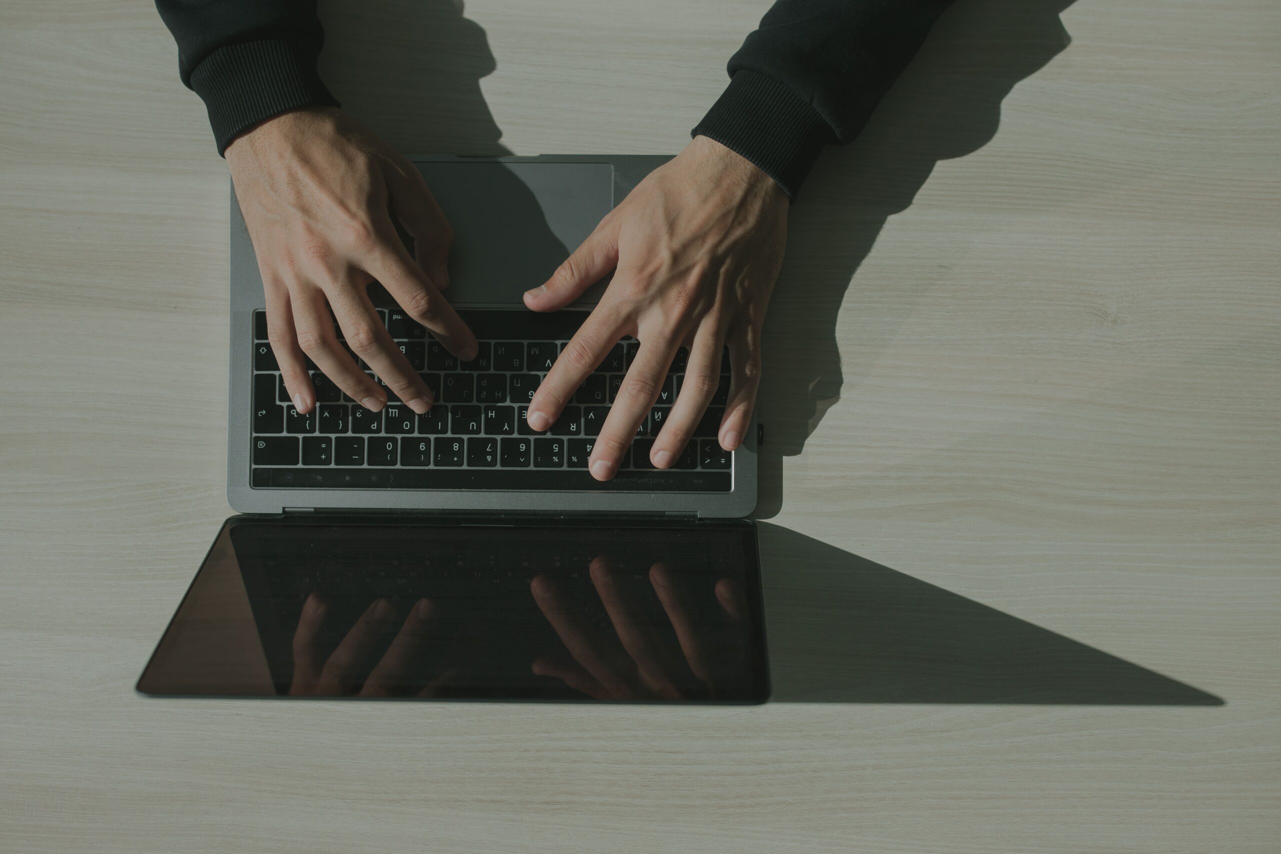 Χέρια πληκτρολογούν σε laptop από ψηλά για διαχείριση email marketing