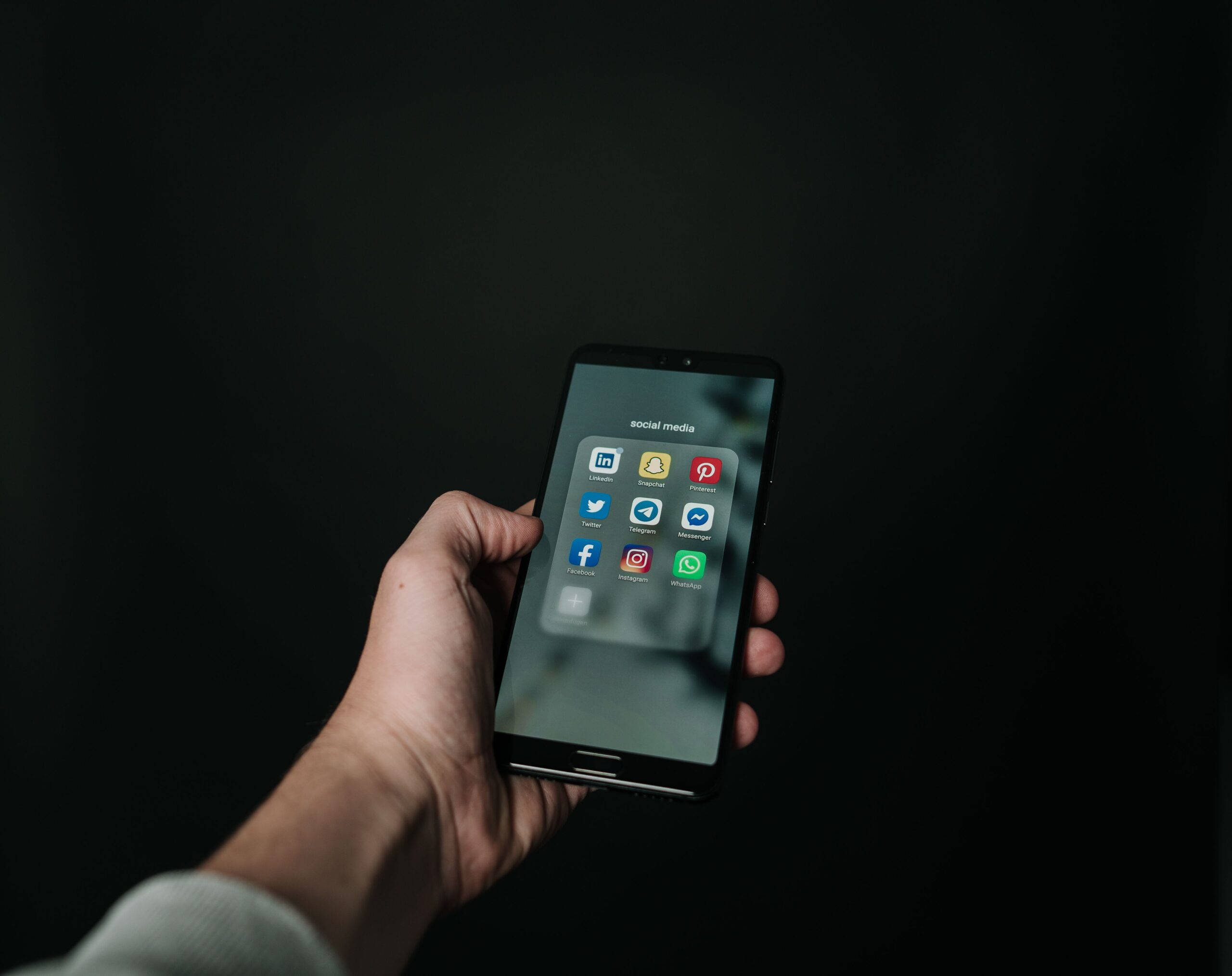 Κάθετα Βίντεο - χέρι κρατά smartphone με εφαρμογές social media σε σκοτεινό φόντο